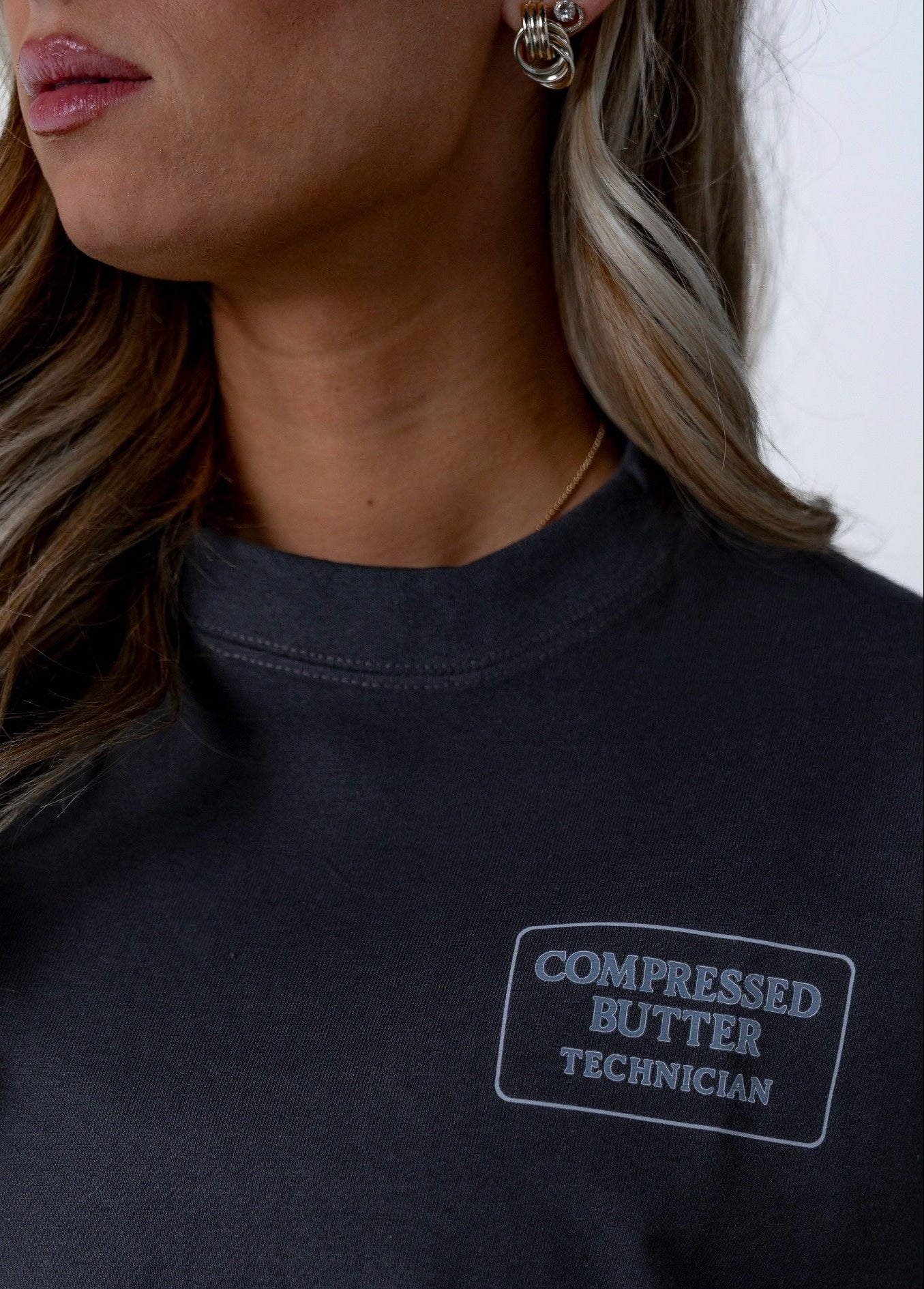 Person wearing a Dark grey shirt with 'Compressed Butter Technician' Logo 