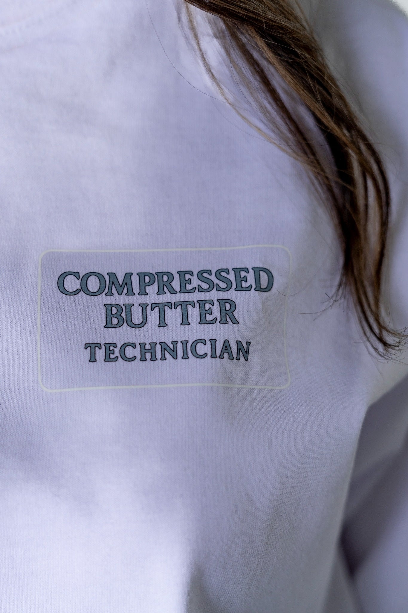 Label on a white shirt with 'Compressed Butter Technician' text