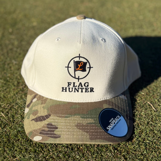 White and camouflage baseball cap with 'Flag Hunter' logo on grass