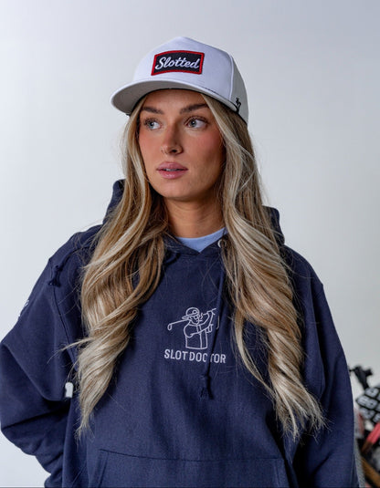 Person wearing a navy hoodie with 'Slotdoctor' logo and a white cap with red and blue text.